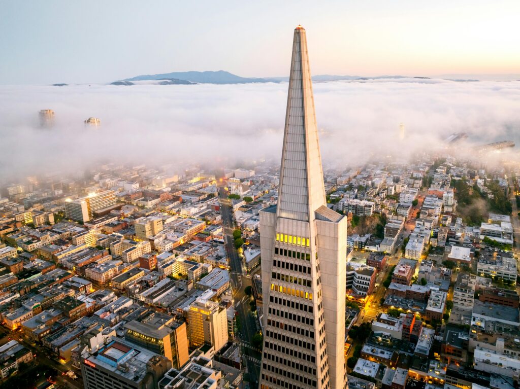 Stunning aerial view of San Francisco skyline enveloped in fog, featuring the Transamerica Pyramid at sunrise.